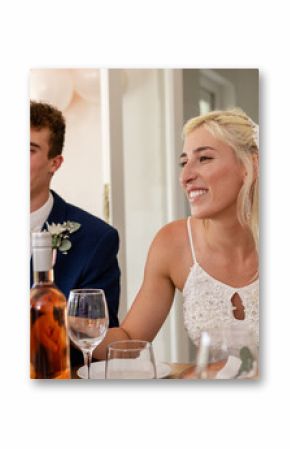 Bride and groom smiling at reception table, enjoying wedding celebration