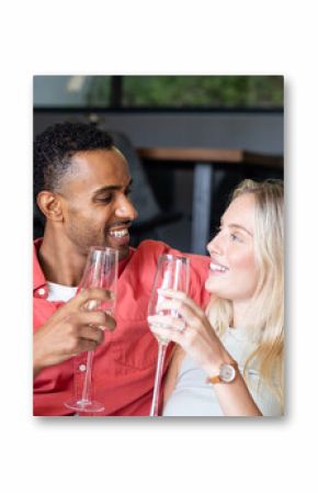 Couple celebrating at home, smiling and toasting with champagne glasses
