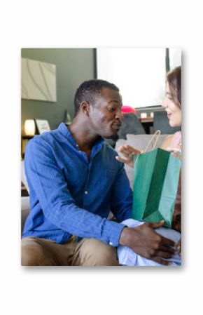 Couple exchanging gift on sofa, smiling and enjoying special moment at home