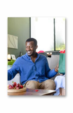 Couple celebrating at home, exchanging gifts and enjoying wine with snacks