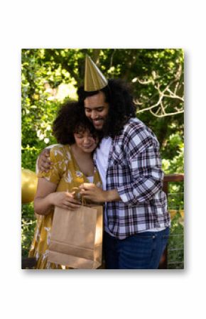 Celebrating outdoors, couple hugging and exchanging gifts at festive party