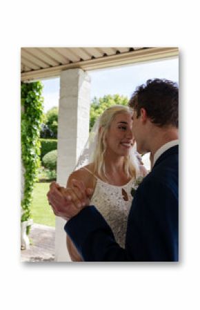 Bride and groom dancing joyfully under pergola, sharing loving moment