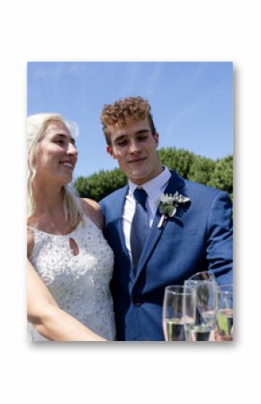 Bride and groom celebrating outdoors, smiling and holding champagne glasses