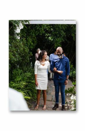 Couple walking arm in arm through garden, smiling and enjoying wedding celebration