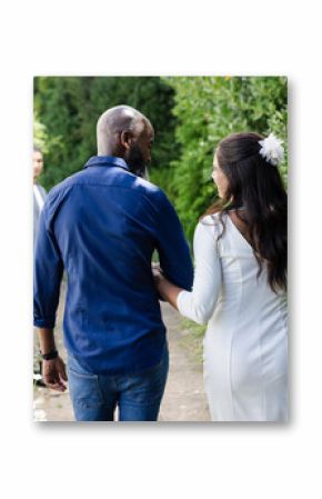 Bride and groom walking arm in arm through lush garden, smiling joyfully