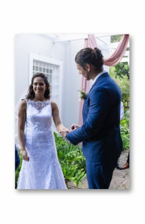 Bride and groom exchanging vows outdoors, surrounded by joyful friends and family