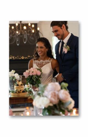 Bride and groom smiling, holding bouquet, celebrating wedding reception indoors
