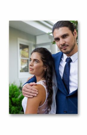 Bride and groom posing together outdoors, embracing and looking content