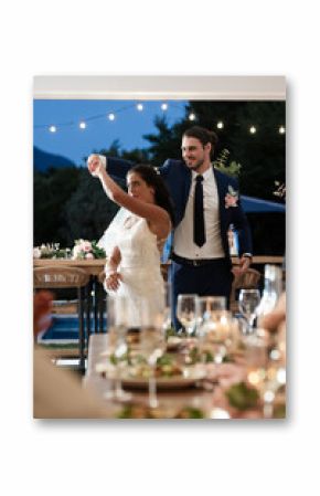 Bride and groom dancing joyfully at outdoor wedding reception under string lights