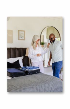 Couple packing suitcase in bedroom, preparing for wedding day celebration