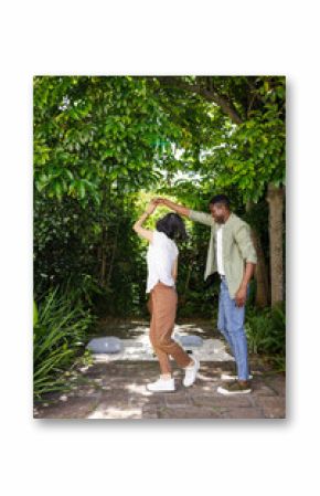 Couple dancing joyfully under lush green trees in garden, celebrating love