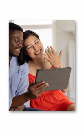 Happy couple video chatting, showing engagement ring, sitting together at home