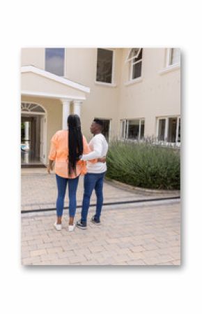 African American couple standing outside house, embracing and enjoying view