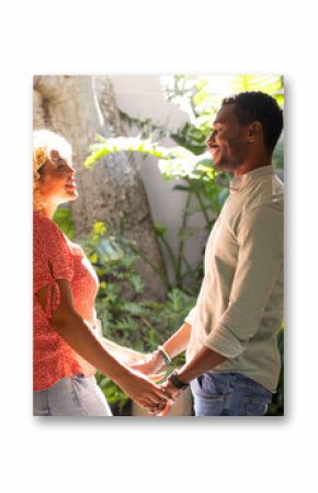 Couple holding hands and smiling warmly in lush garden setting