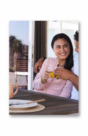 Couple enjoying morning coffee on patio, smiling and embracing each other warmly
