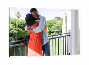 Couple embracing on balcony, enjoying sunny day at outdoor wedding venue