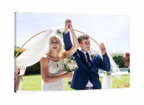 Bride and groom celebrating outdoors, holding hands and smiling joyfully
