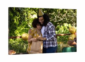 Celebrating outdoors, couple hugging and exchanging gifts at festive party