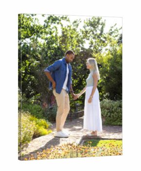 Couple holding hands in sunny garden, enjoying romantic moment together