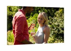 Couple enjoying champagne in sunny garden, celebrating special moment together