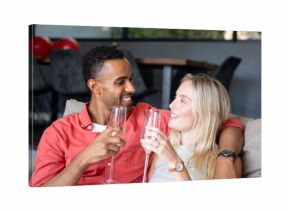 Couple celebrating at home, smiling and toasting with champagne glasses