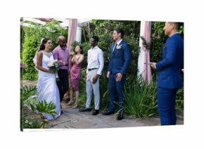 Bride in white dress walking towards groom in blue suit, guests smiling warmly