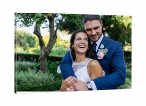Bride and groom embracing joyfully in lush garden, celebrating their wedding day