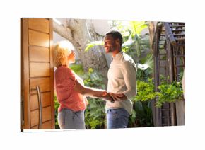 Couple holding hands and smiling, enjoying sunny day in lush garden