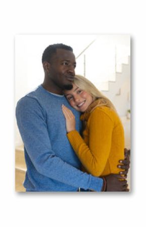 Happy multiracial couple embracing at home, enjoying cozy holiday moments together