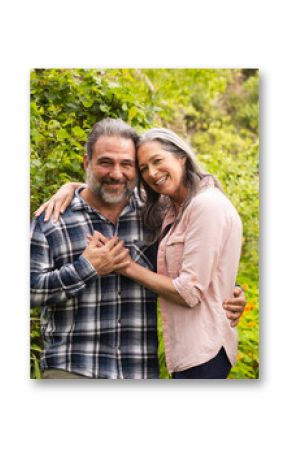 Happy mature couple embracing in lush garden, enjoying nature together, outdoors