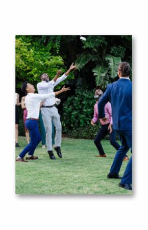 Catching bouquet joyfully, guests celebrating wedding in garden setting together