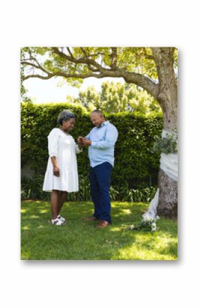 At wedding, Exchanging rings under tree, senior couple celebrating special moment in garden
