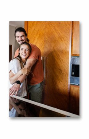In new home, Couple laughing and hugging in modern kitchen, enjoying quality time together, at home