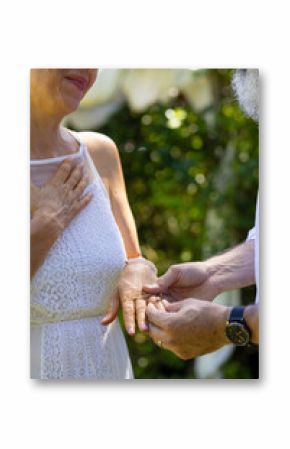 Senior couple exchanging rings in outdoor ceremony, celebrating love and commitment