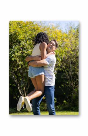 Young couple embracing and lifting each other in joyful outdoor moment