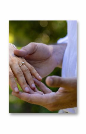 Showing engagement ring, senior bride and groom holding hands outdoors, at outdoor wedding