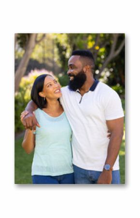 Smiling couple embracing and looking at each other in sunny garden