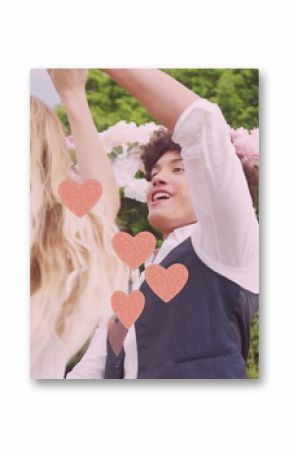 Image of pink hearts over happy diverse couple dancing in garden on wedding day