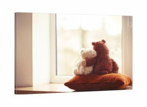 Two embracing teddy bear toys sitting on window-sill