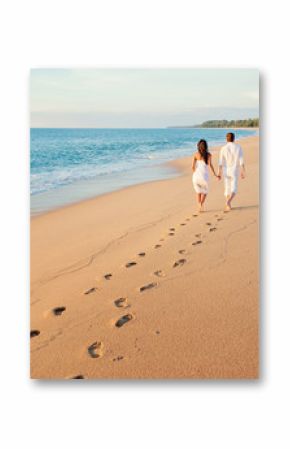 Honeymoon at the sea. Back view of loving couple walking away with footprints at sandy beach