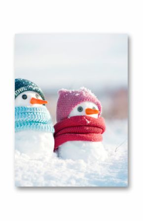 Two little snowmen the girl and the boy in knitted caps and scarfs on snow in the winter. Festive background with a lovely snowman. Christmas card, copy space