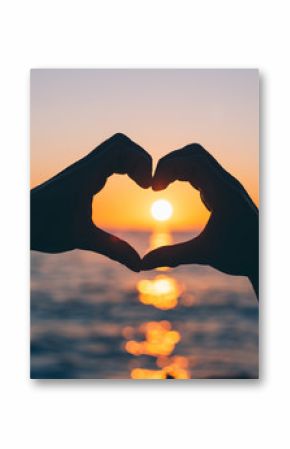 Silhouette of male hands in the shape of a heart at sunset