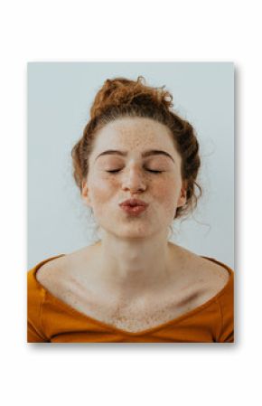 Woman portrait. Style. Beautiful girl with freckles is pouting lips at camera, on a white background