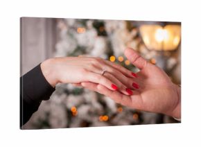 Man`s hand holds in the woman`s hand with a ring put on.  Romantic proposal to a woman.  Winter love.