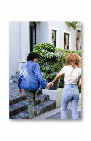 Young diverse couple holding hands walking outside, enjoying sunny day together