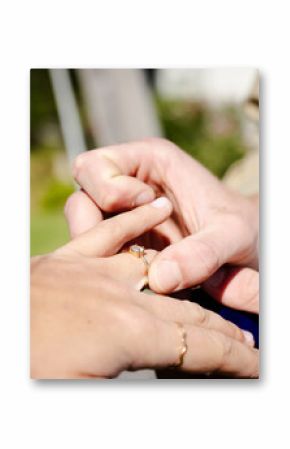 Placing engagement ring on partner's finger during outdoor wedding celebration