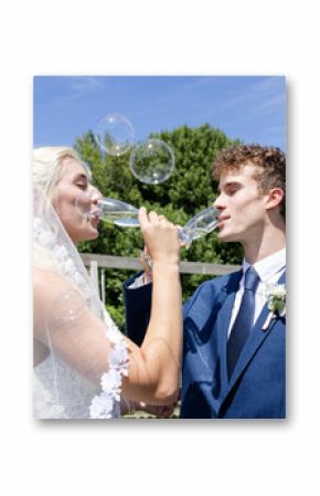 Bride and groom joyfully toasting with champagne glasses outdoors under sunny sky