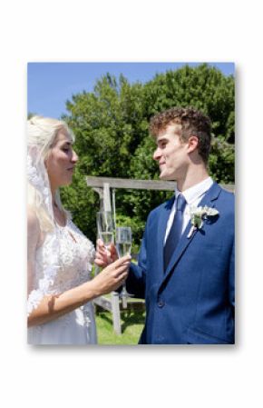 Bride and groom toasting with champagne glasses in beautiful outdoor garden