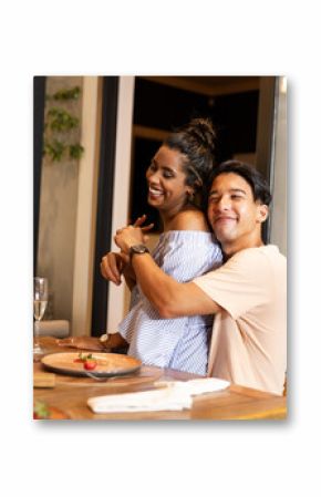 Young couple enjoying cozy dinner at home, smiling and embracing warmly