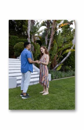 Young couple holding hands and smiling in lush garden setting